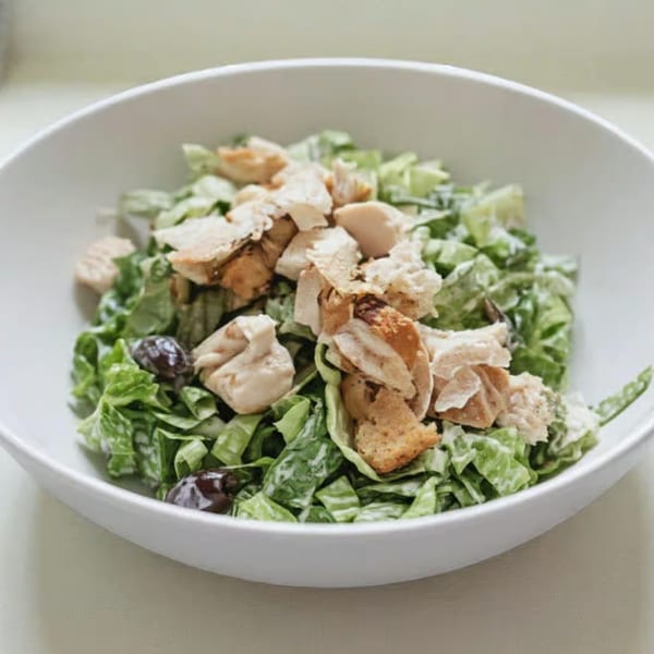 Caesar salad with chicken, croutons, and olives in a white bowl at Tony's Pizzeria.