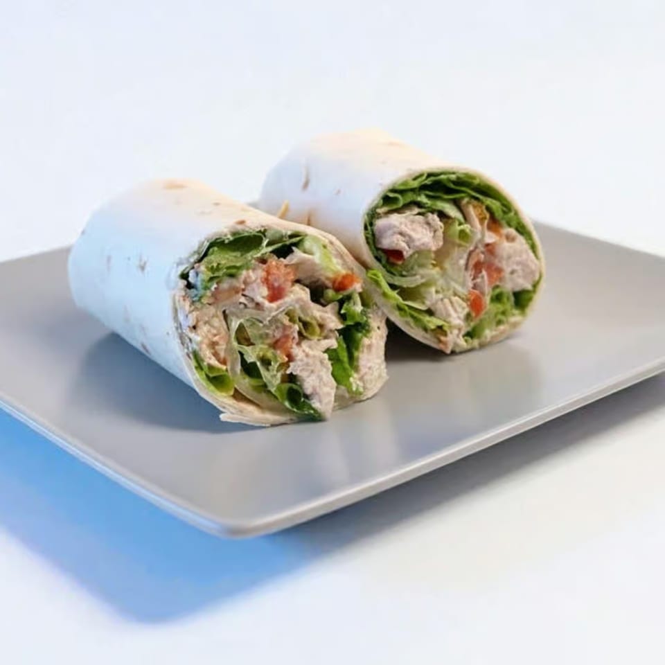 Two chicken wraps, filled with lettuce and tomatoes, on a gray rectangular plate.