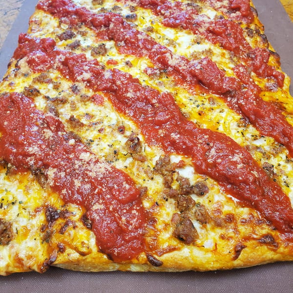 Tony's Pizzeria's square pizza with melted cheese, sausage, and stripes of red sauce.